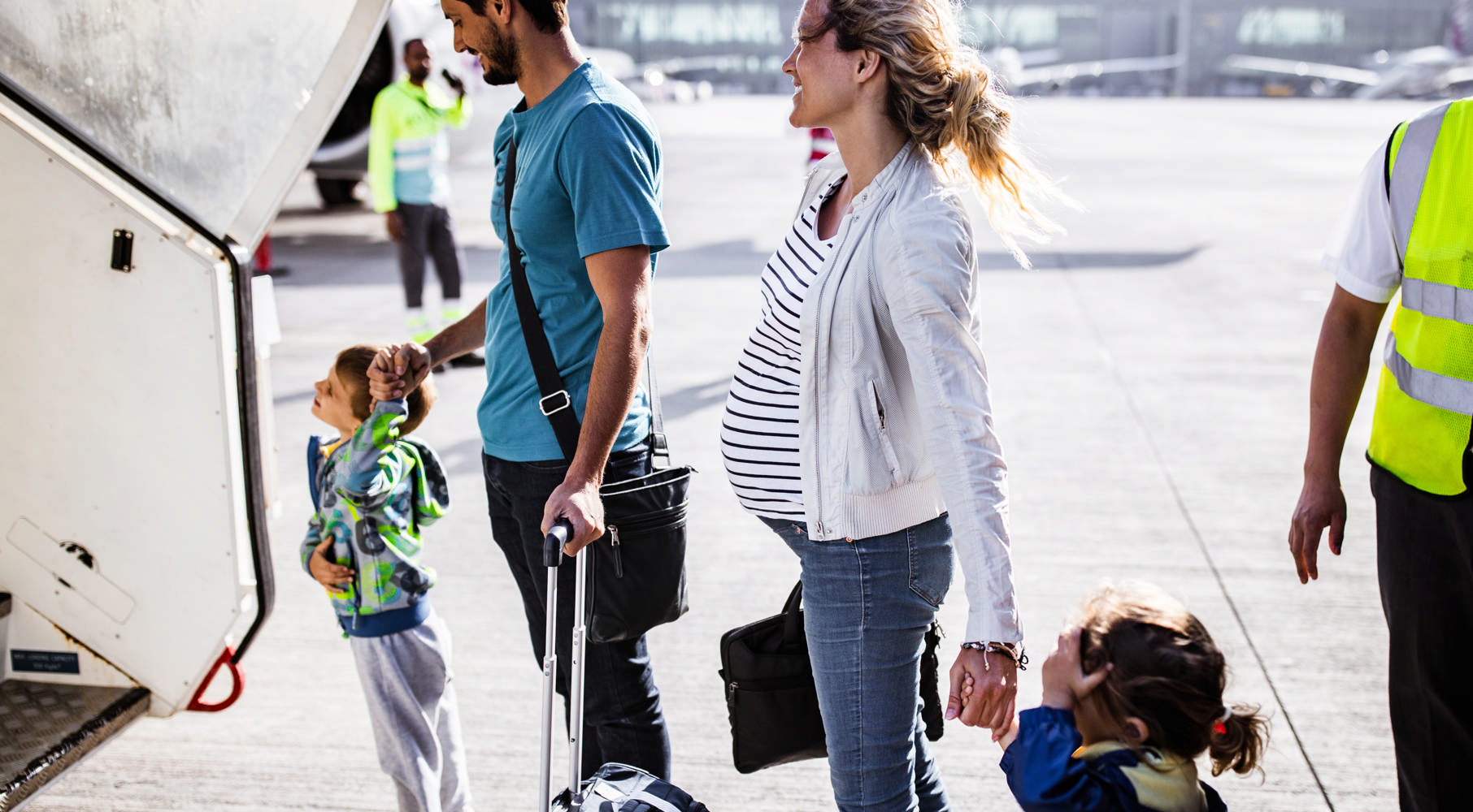 Far, gravid mor og to børn på vej til fly